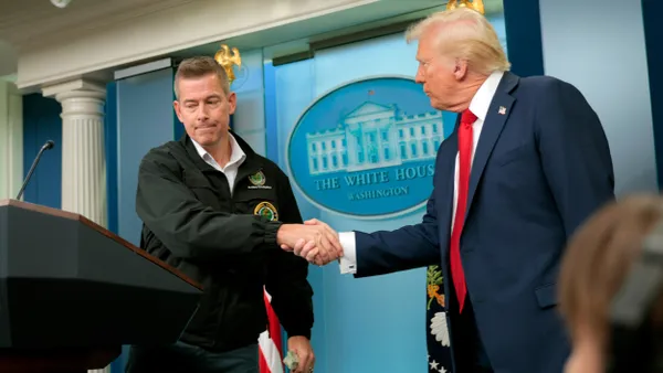 Two men shaking hands in front of a sign that reads "The White House - Washington."