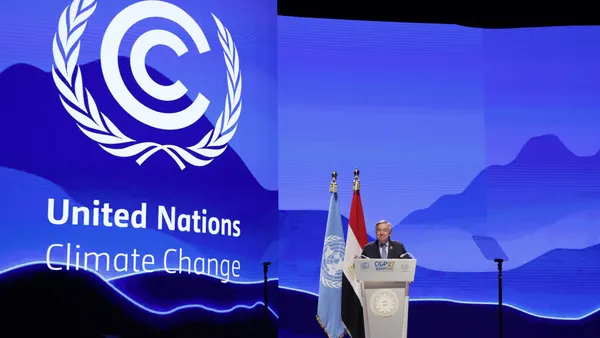 Man standing at podium in front of blue backdrop on stage