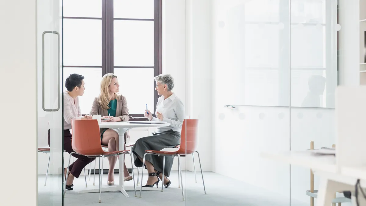 Three women sitting at table in modern office