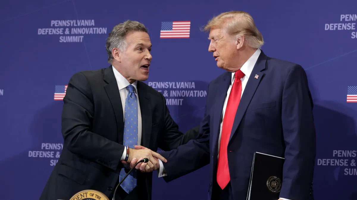 Two people in suits and ties shaking hands with a blue background.