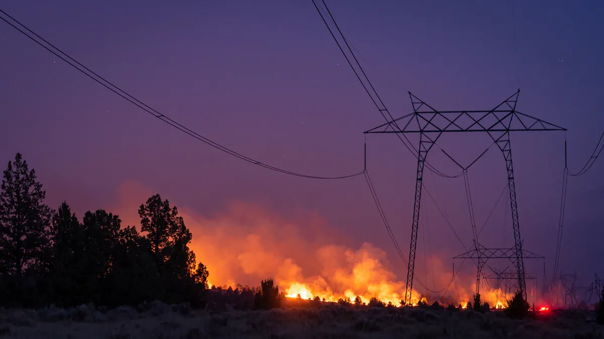 A forest fire burns under a high voltage transmission line in California.