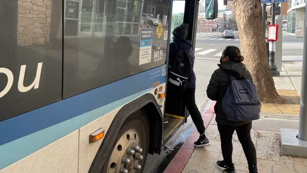 People entering a bus stopped at a curb.
