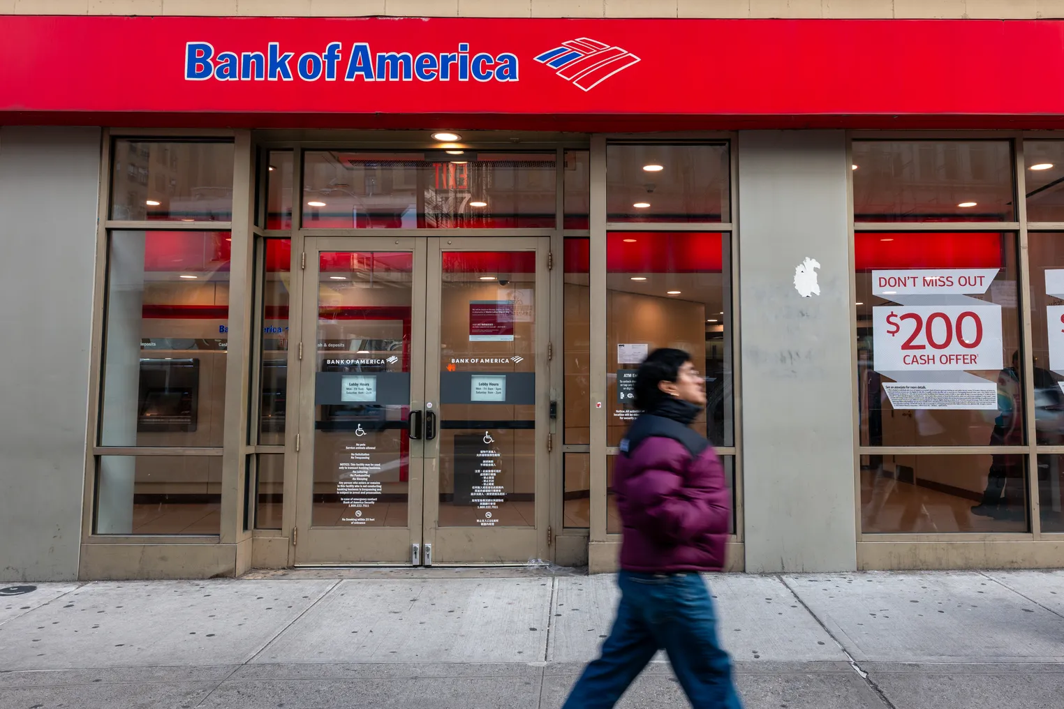 A person walks by a Bank of America branch location