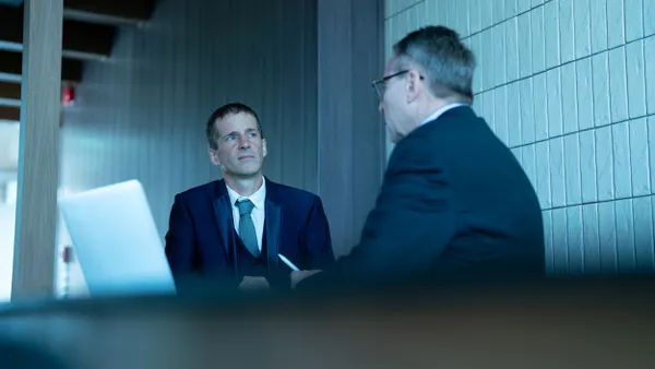 Two businessmen meet in a conference room.