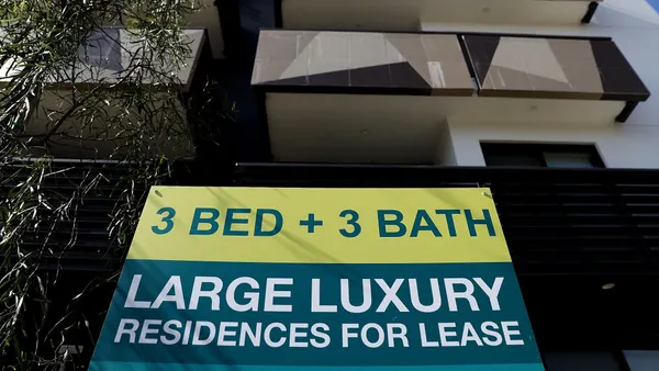 A for lease sign is posted in front of an apartment building.
