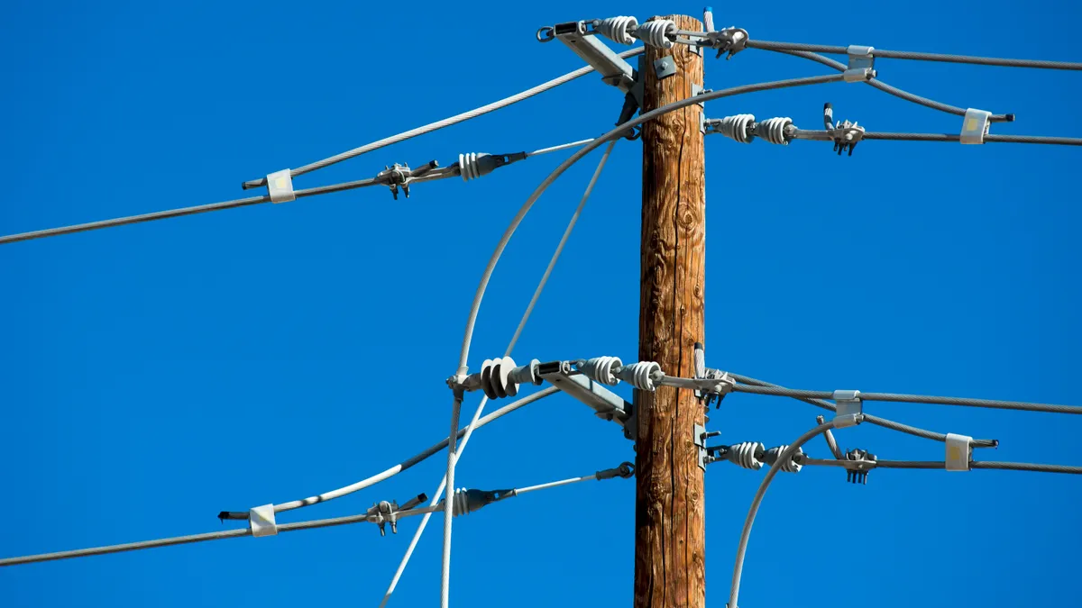 Image shows the top of a utility pole with connecting wires.