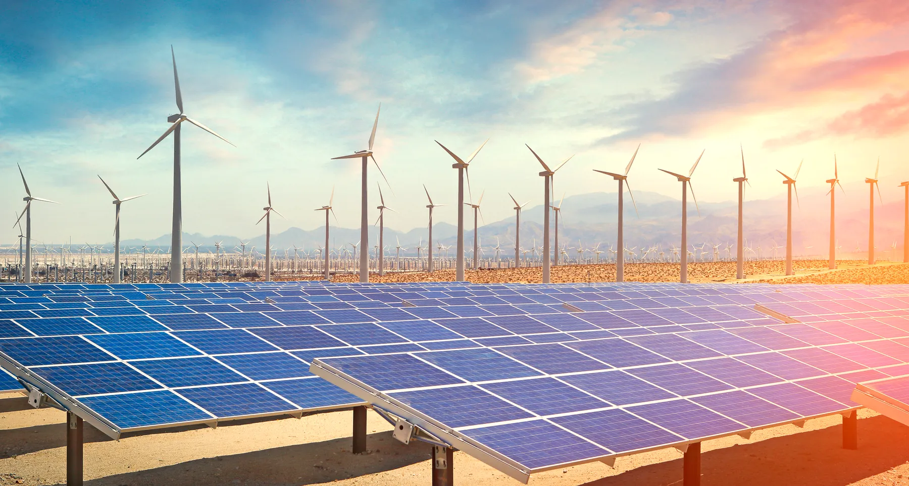 Solar panels and wind turbines in the desert producing renewable energy.