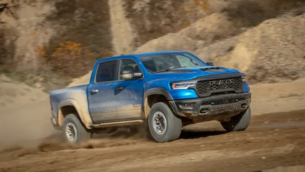 A blue 2025 Ram 1500 RHO drives on an offroad dirt trail.