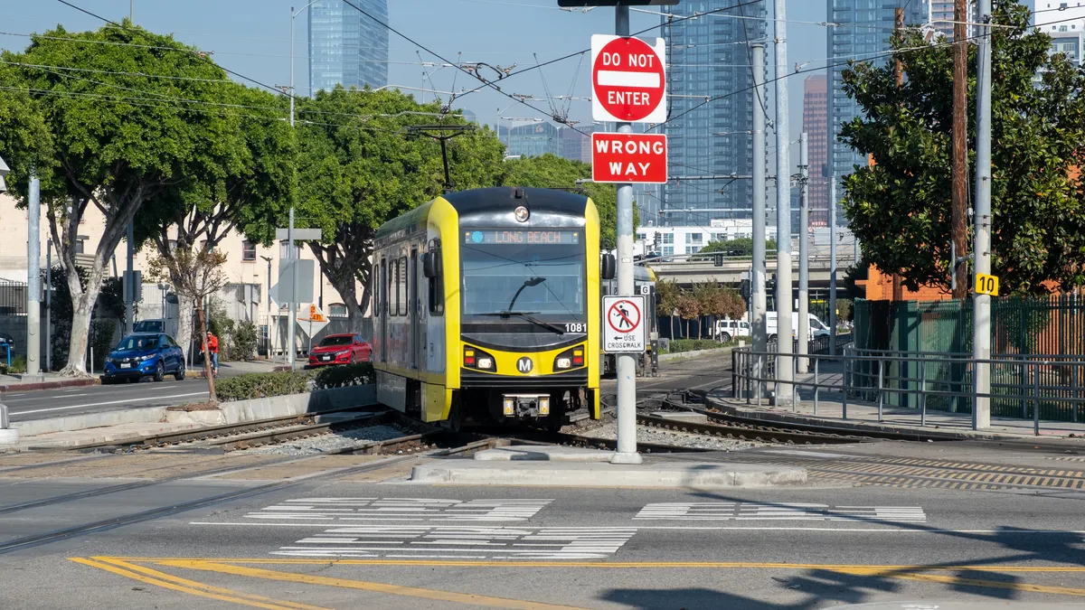 An LA Metro light rail train turning across a street intersection in downtown Los Angeles.