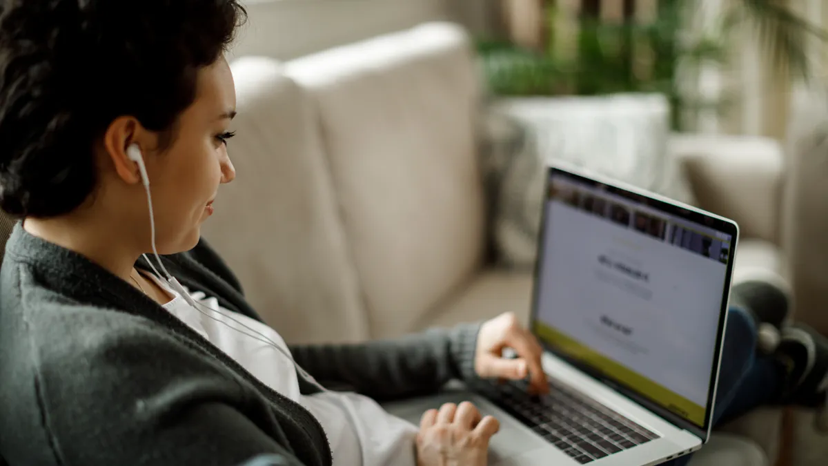 Young woman using laptop and listening to music at home