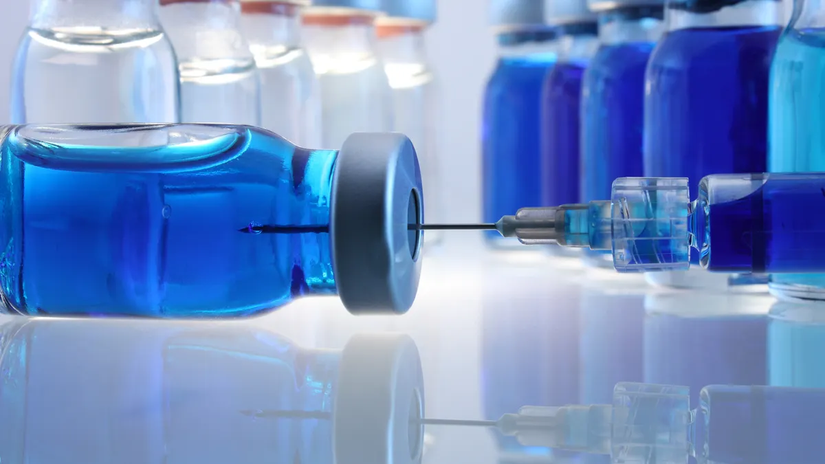 Laboratory bottles with blue content and a syringe