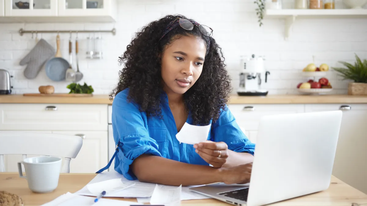 Portrait of beautiful serious woman with curly hair keyboarding on laptop pc