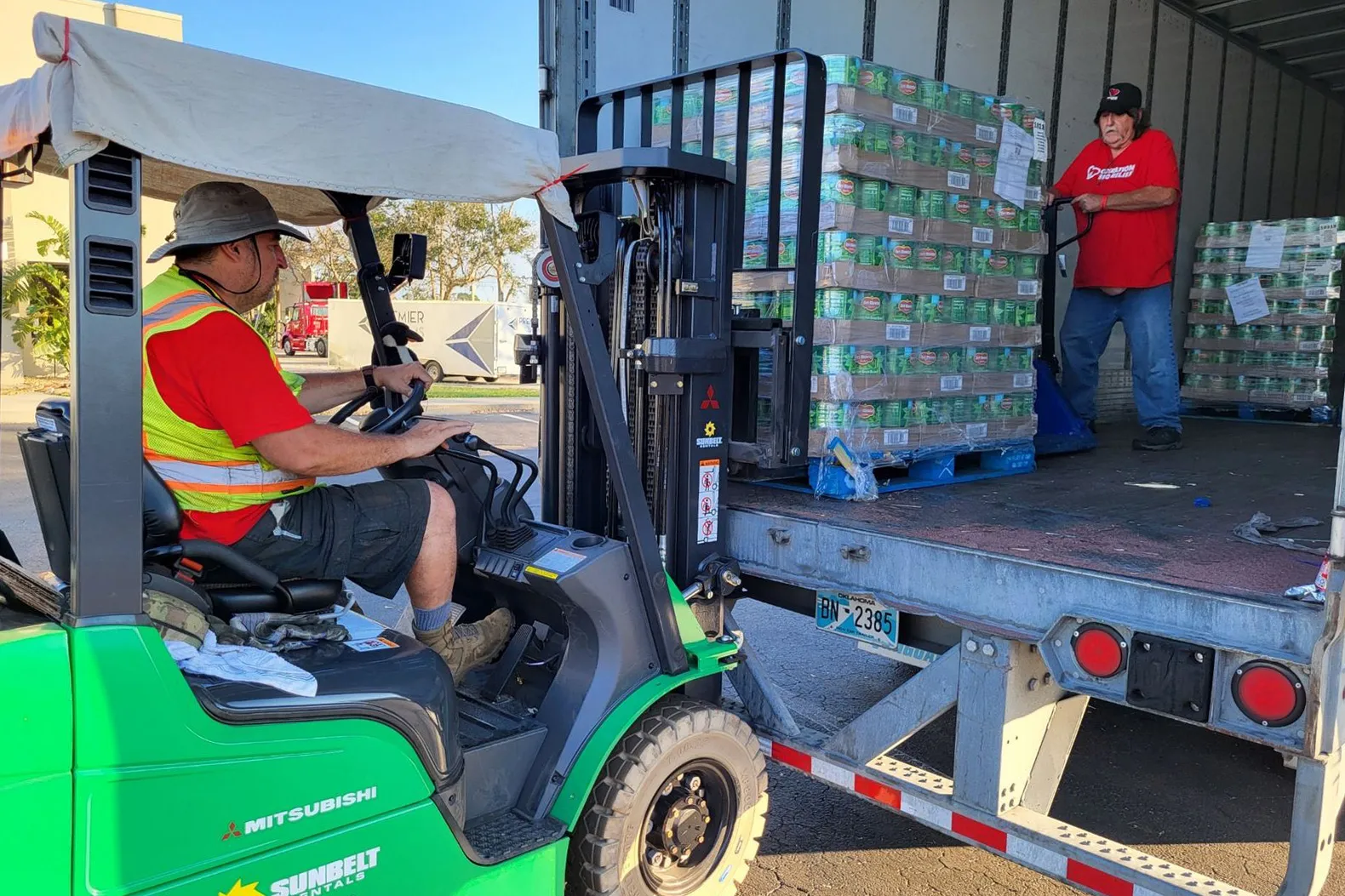 A forklift driver loads a truck with canned goods.