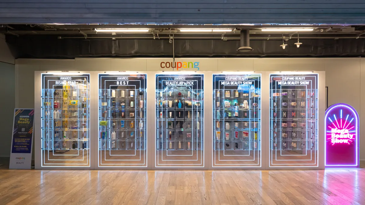 Image shows interior storefront of Coupang featuring neon displays.