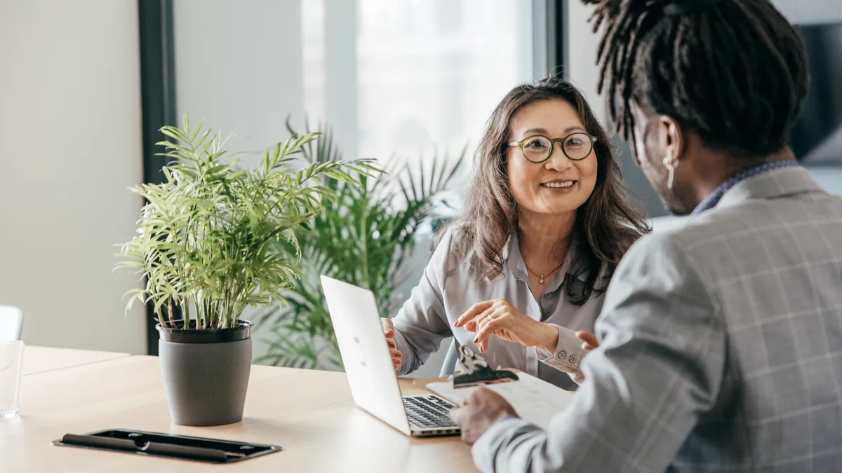 Two people talk in an office.