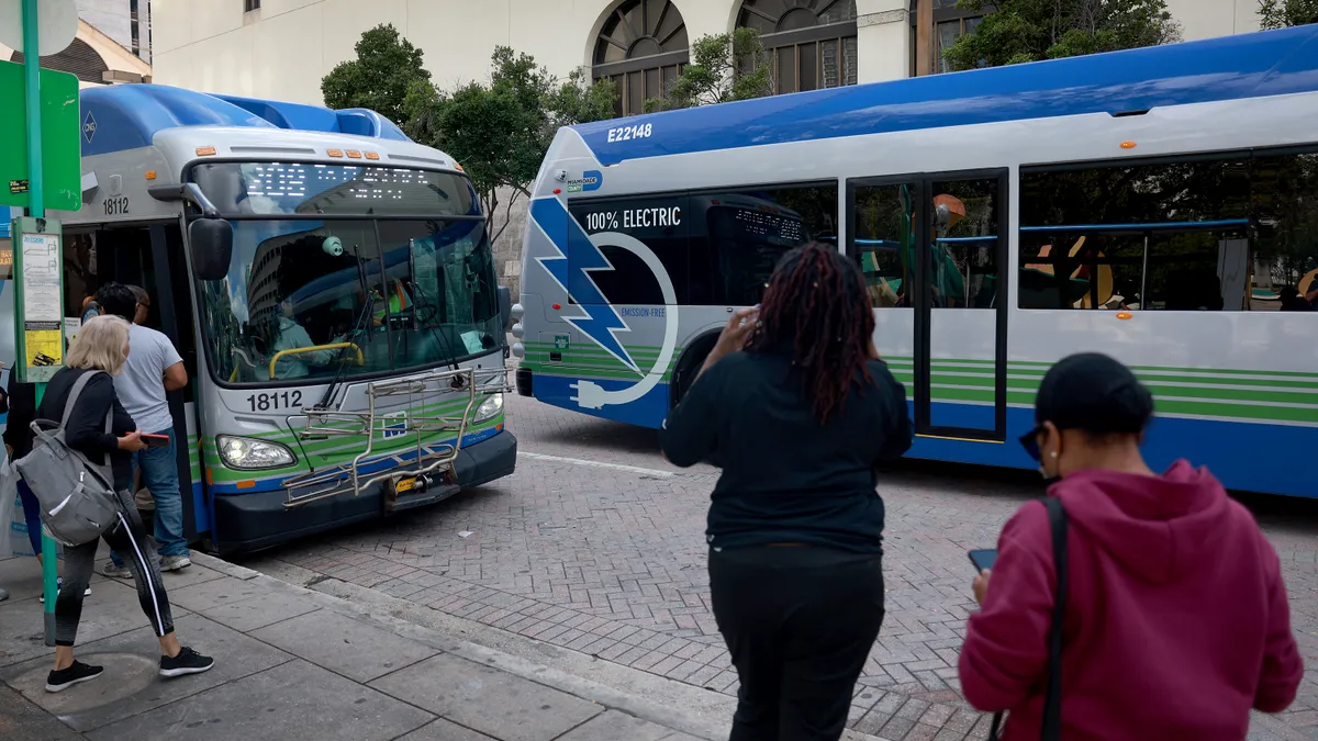 People gather around new electric buses in Miami.