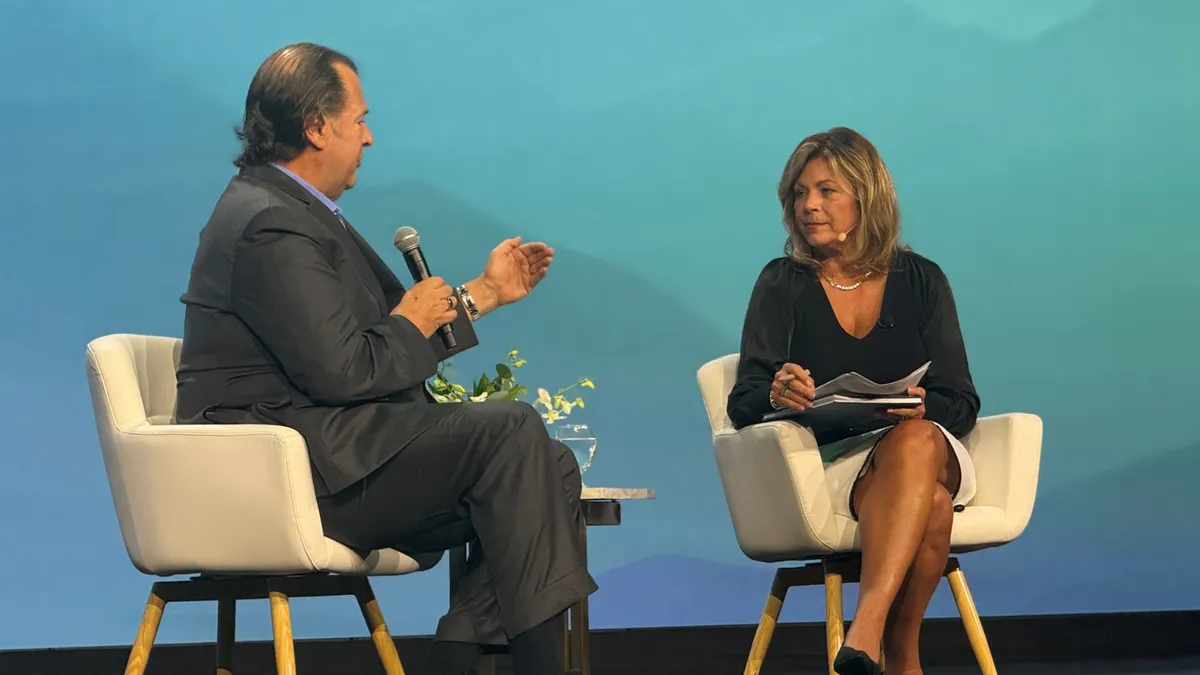 An executive and an analyst sit on stage at a conference.