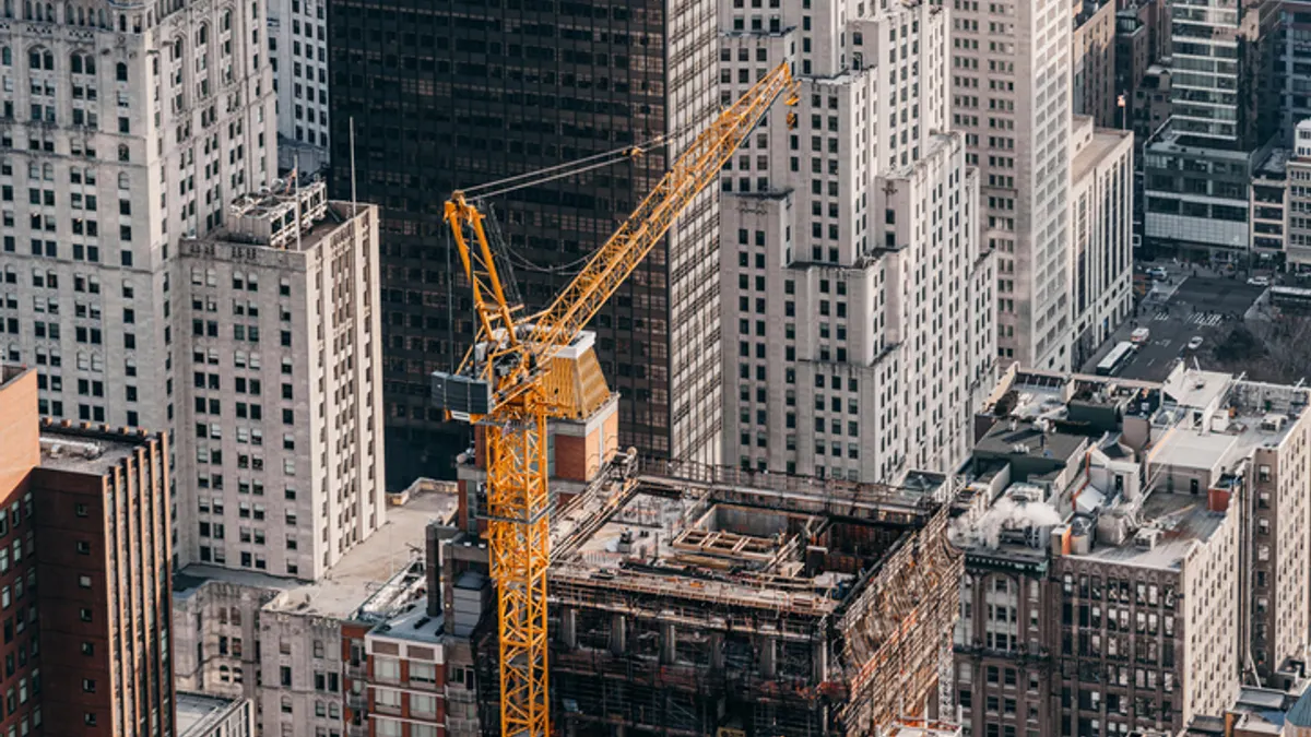 An aerial view shows a crane over several tall buildings in a city.