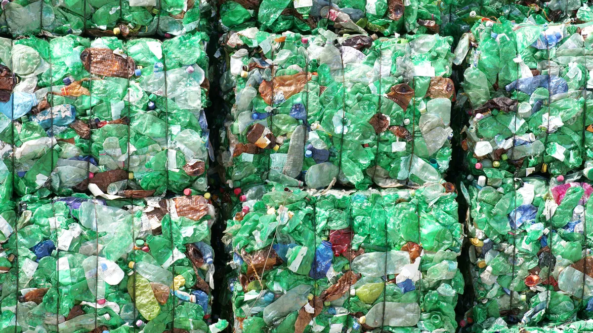 Bales of crushed plastic bottles, most of them green in hue.