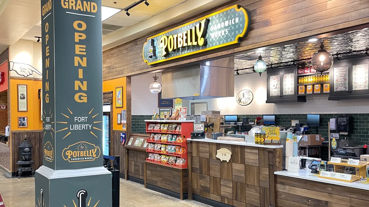 A Potbelly storefront with green decor. A pillar says grand opening.