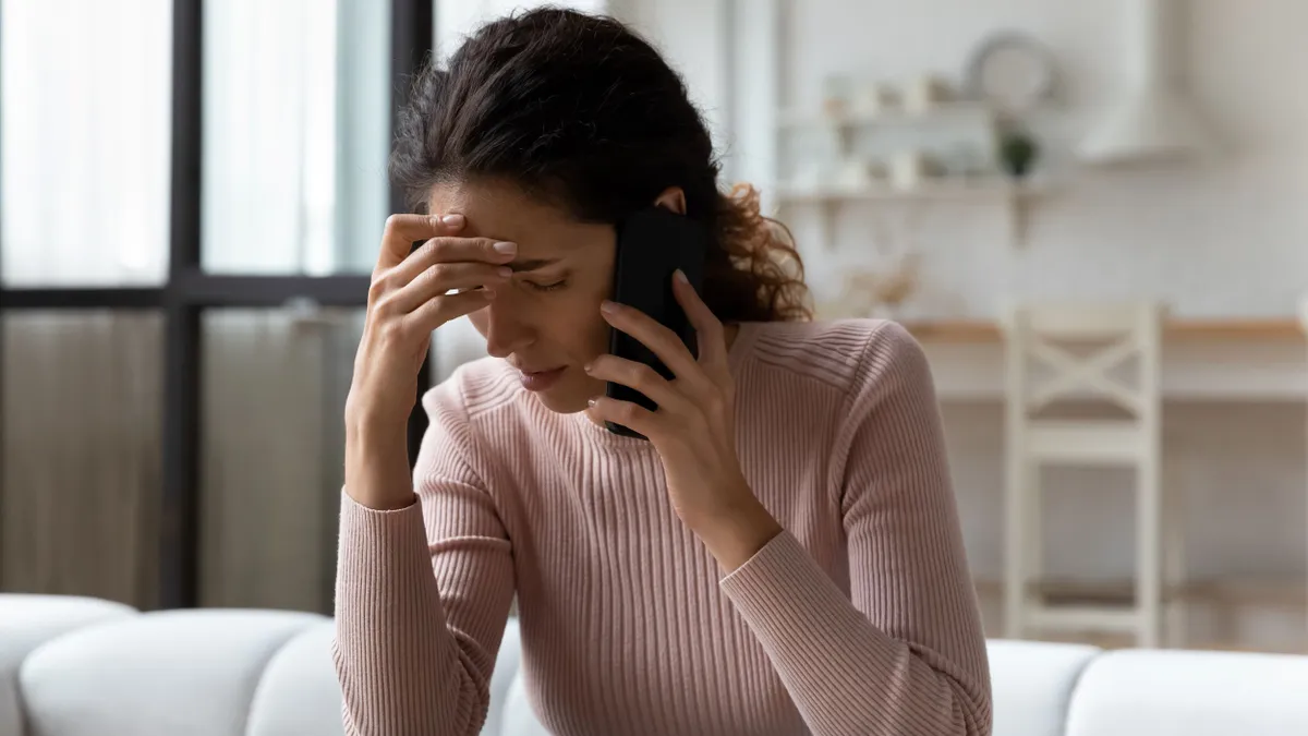 Woman talking on phone having unpleasant conversation and looks stressed.