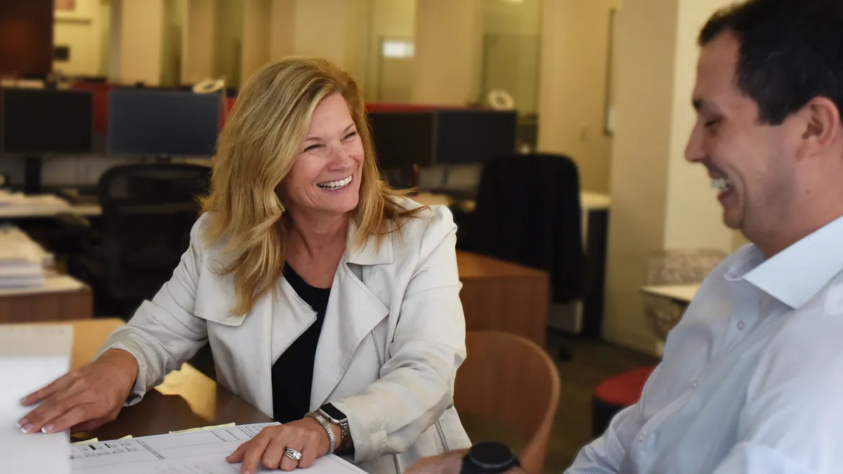 A woman and man laugh in a conference room