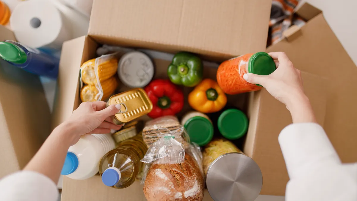 A volunteer packs a box of donated food.