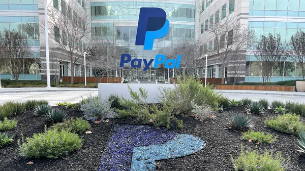 PayPal logo in front of a glass building with shrubery in the foreground