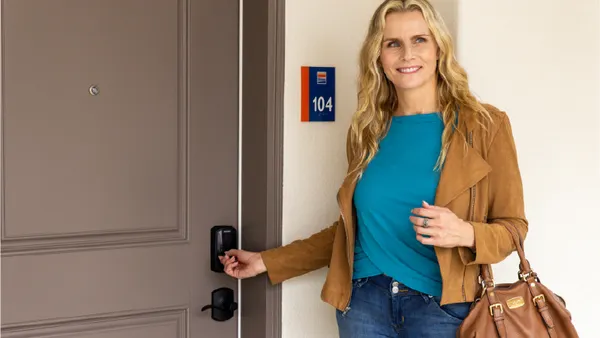 Person standing in front of a door holding a lock.