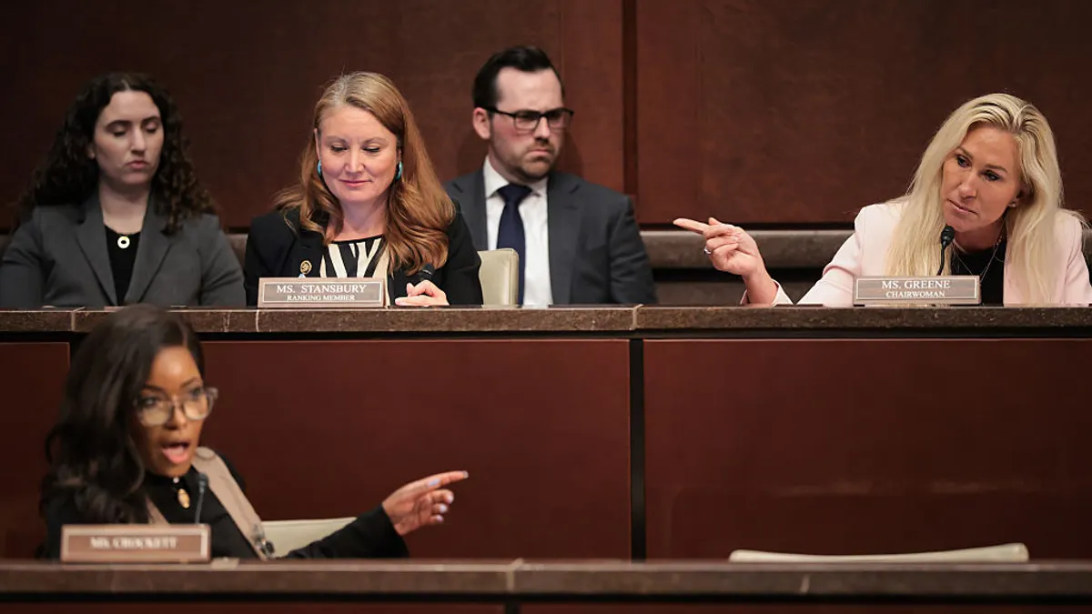 Lawmakers sit in a DOGE subcommittee hearing with pictures of a witness displayed