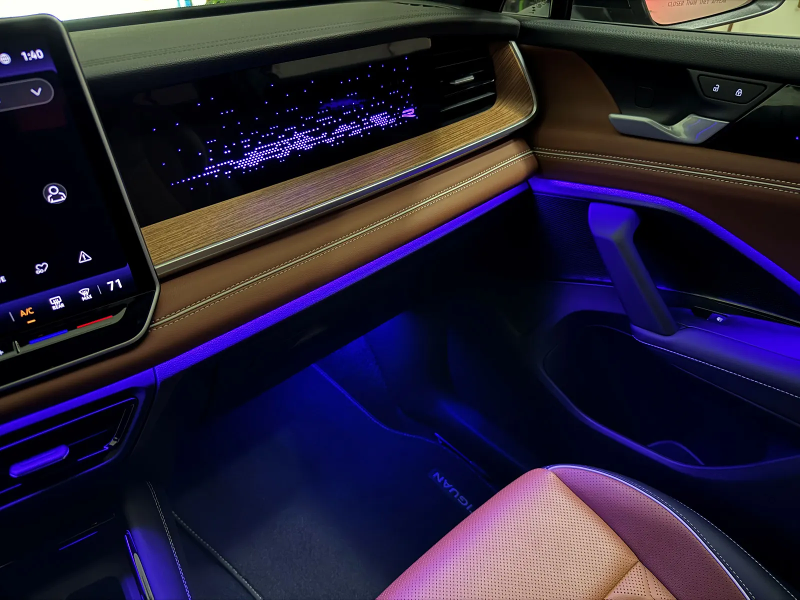 A blue hue accents the floor of the Volkswagen Tiguan SEL R-Line's interior cabin, contrasting nicely with amber-brown leather seats.