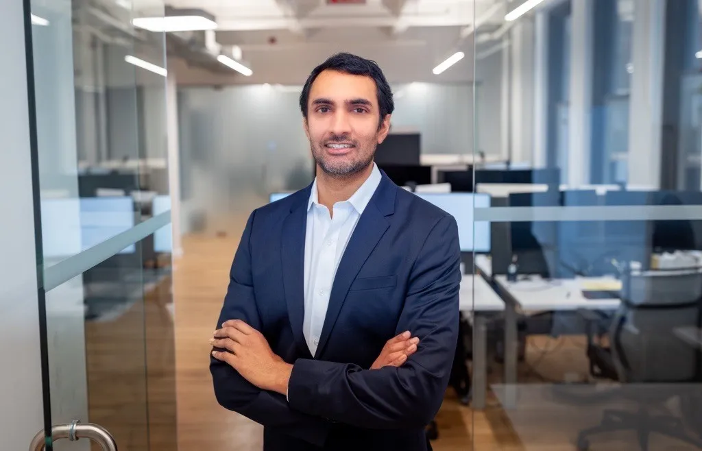 Dr. Sandeep Kulkarni poses arms folded in front of a blurry office space