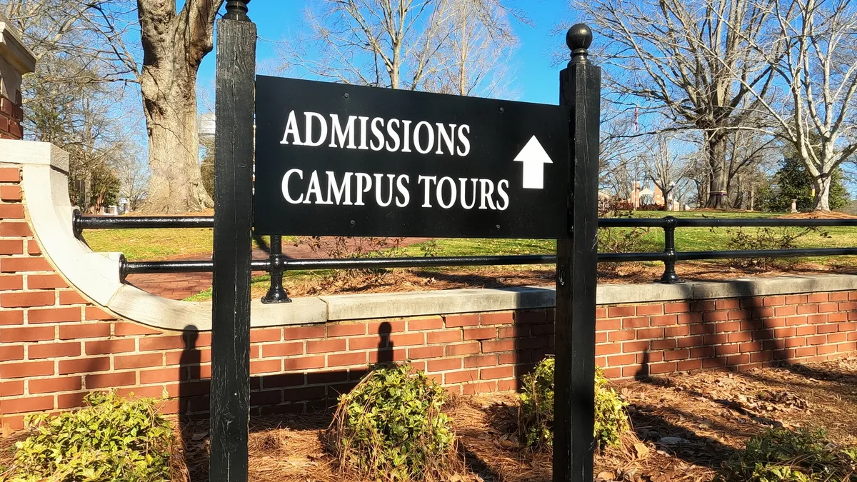 A sign points to a college admissions office.