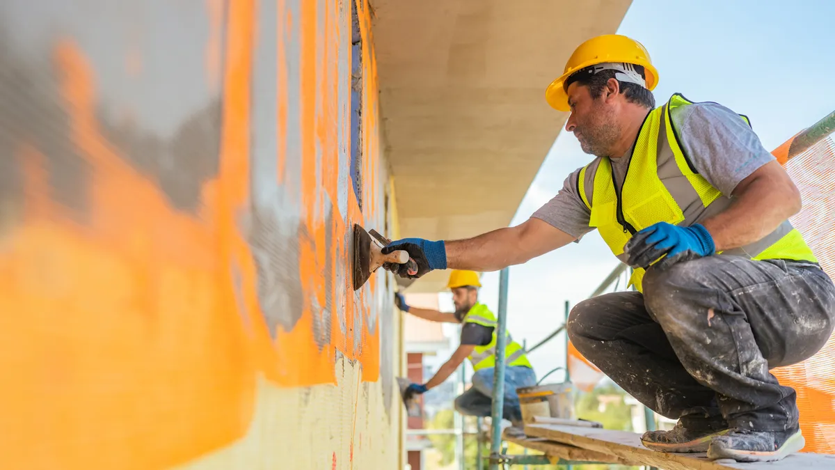 Construction workers applying plaster on building facade