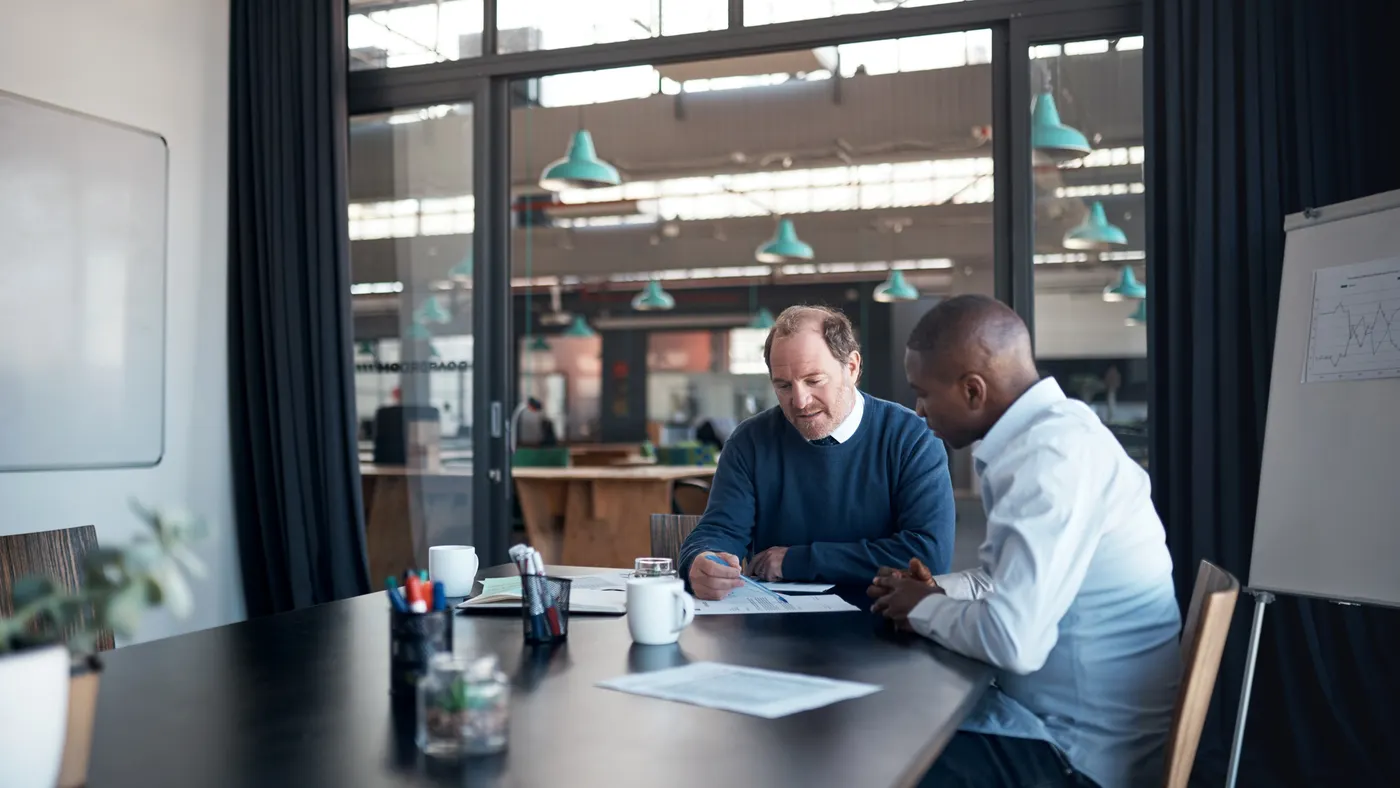 Two businessmen going over paperwork in a modern office
