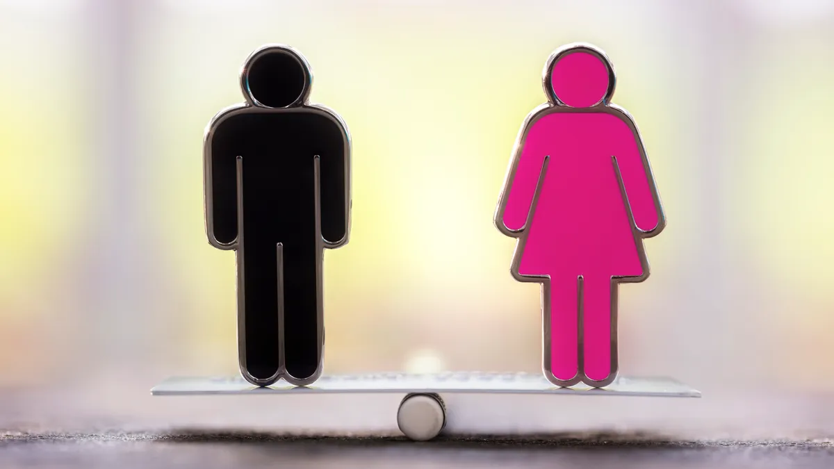 A male symbol and female symbol equally balance on a scale