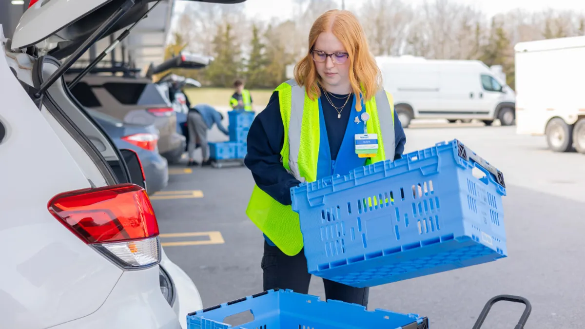 A Walmart employee packs products into a vehicle.