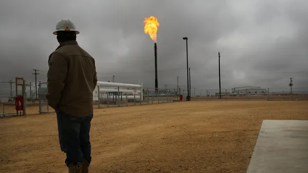 A worker watches as flared natural gas is burned off at Apache Corporations operations at the Deadwood natural gas plant in the Permian Basin in Texas.