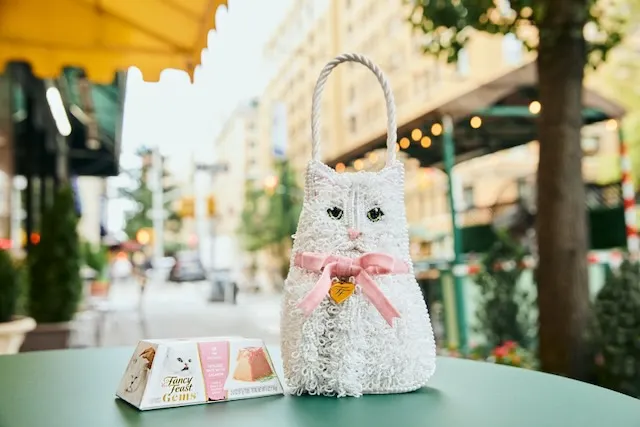 A small white beaded handbag in the shape of a cat.
