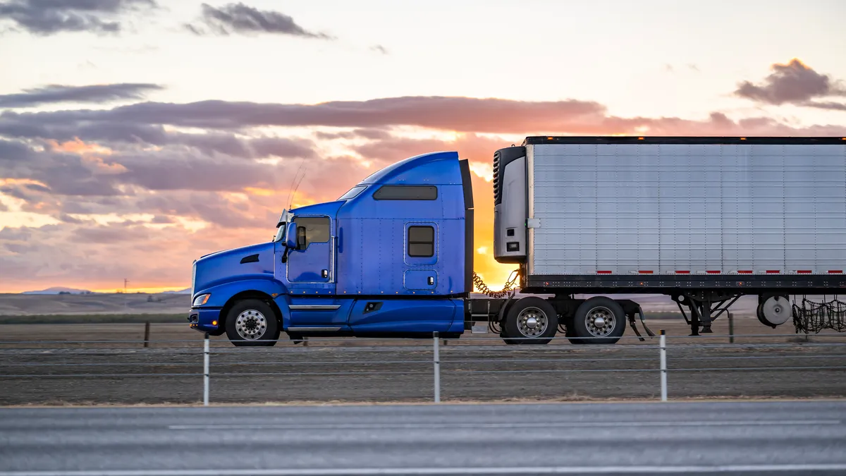 A big rig on the highway road at sunset.