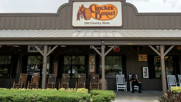A Cracker Barrel sign hangs on the outside of a restaurant.