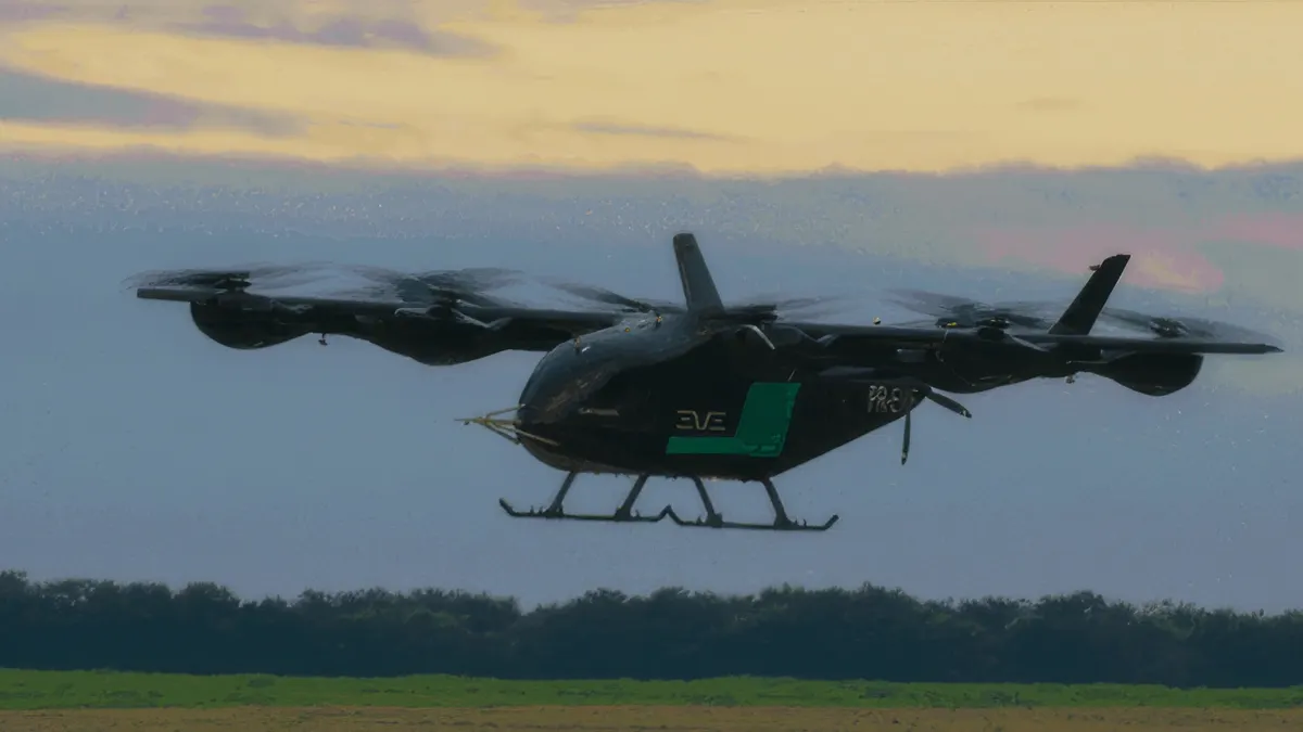 An aircraft with multiple rotors aloft over a field with trees in the background.