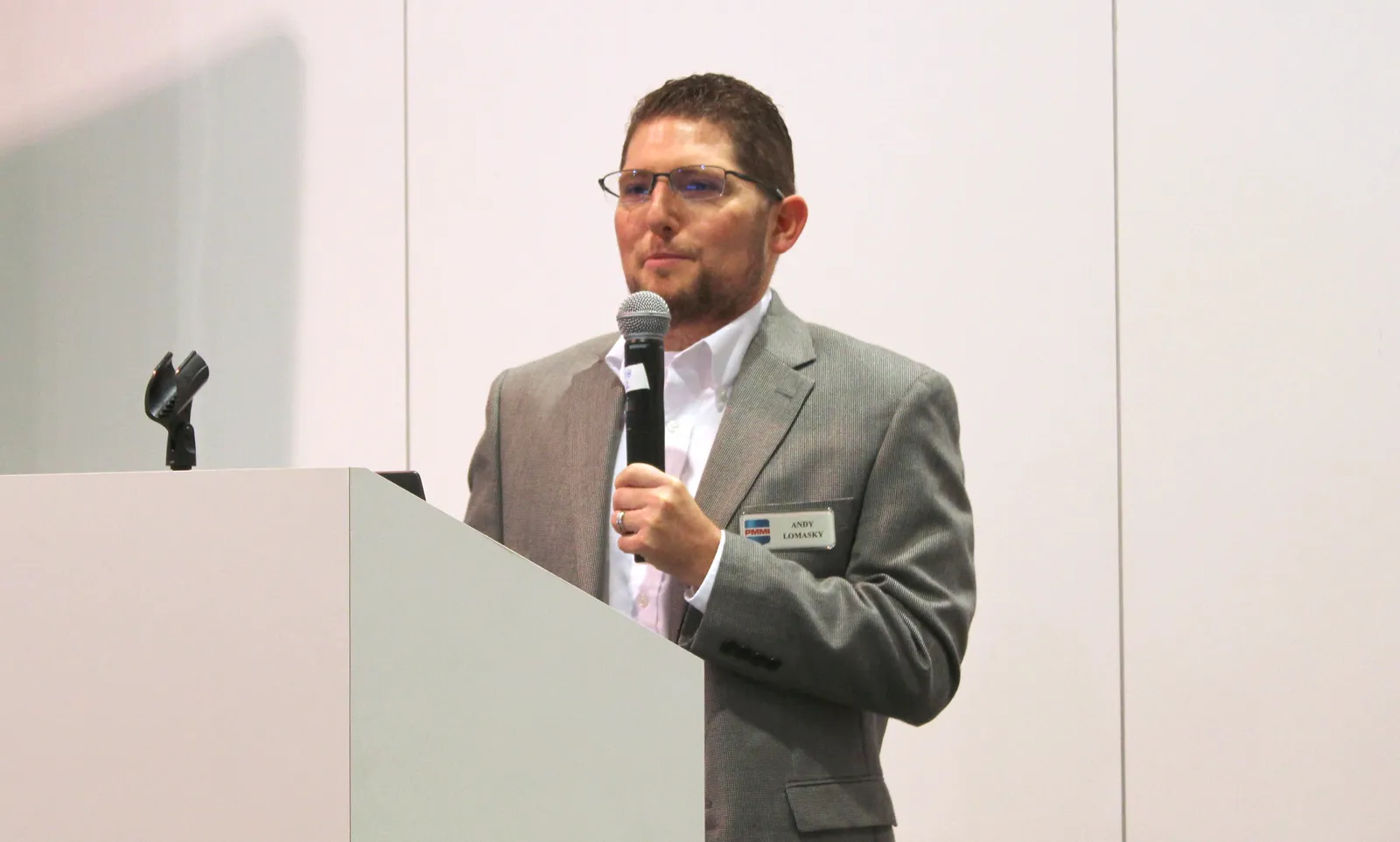 A person speaks from behind a white podium at an event.