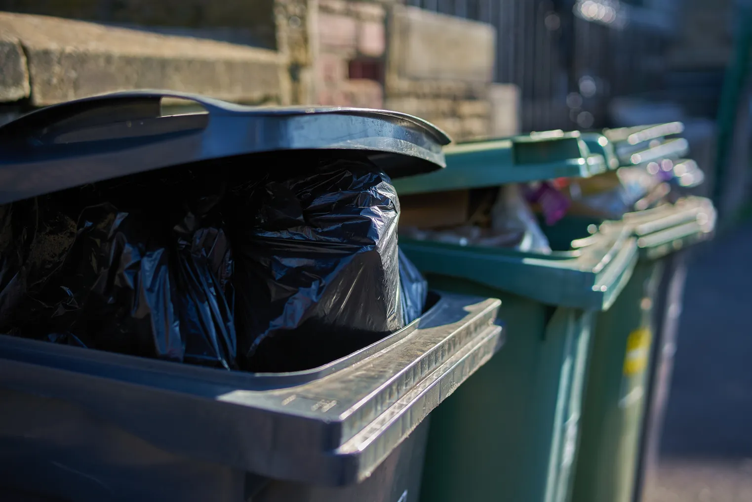 Gray and green garbage cans overfilled with domestic refuse