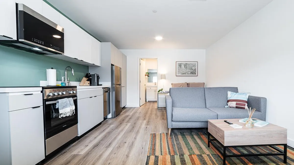 An apartment with a kitchen next to a bed and a sofa.