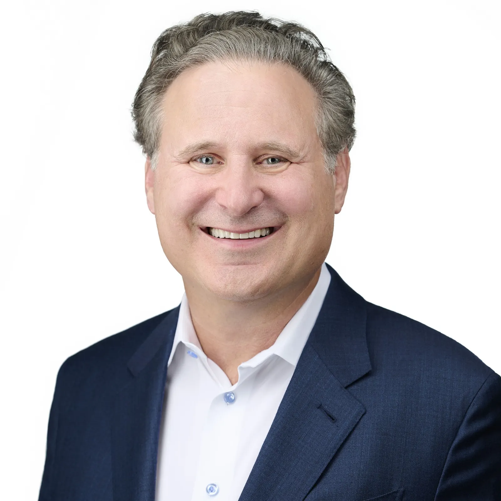 A person wearing a white collared shirt and navy blue suit jacket smiles for a photo.