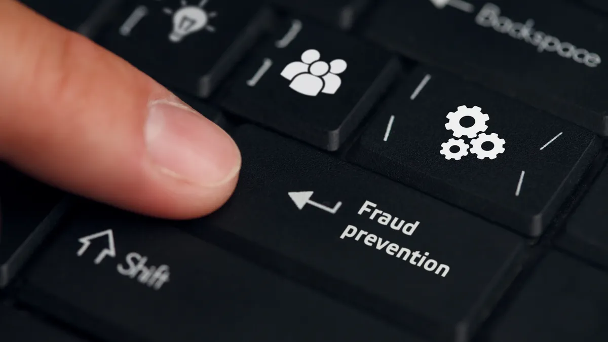 Business, technology, internet and networking concept. Young businessman working on his laptop in the office, select the icon Fraud prevention on the virtual display