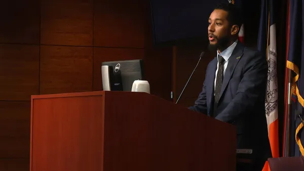 A man in a suit speaks at a lectern