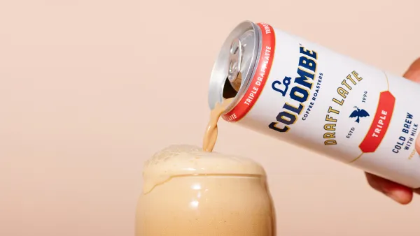 A canned latte is poured into a glass.