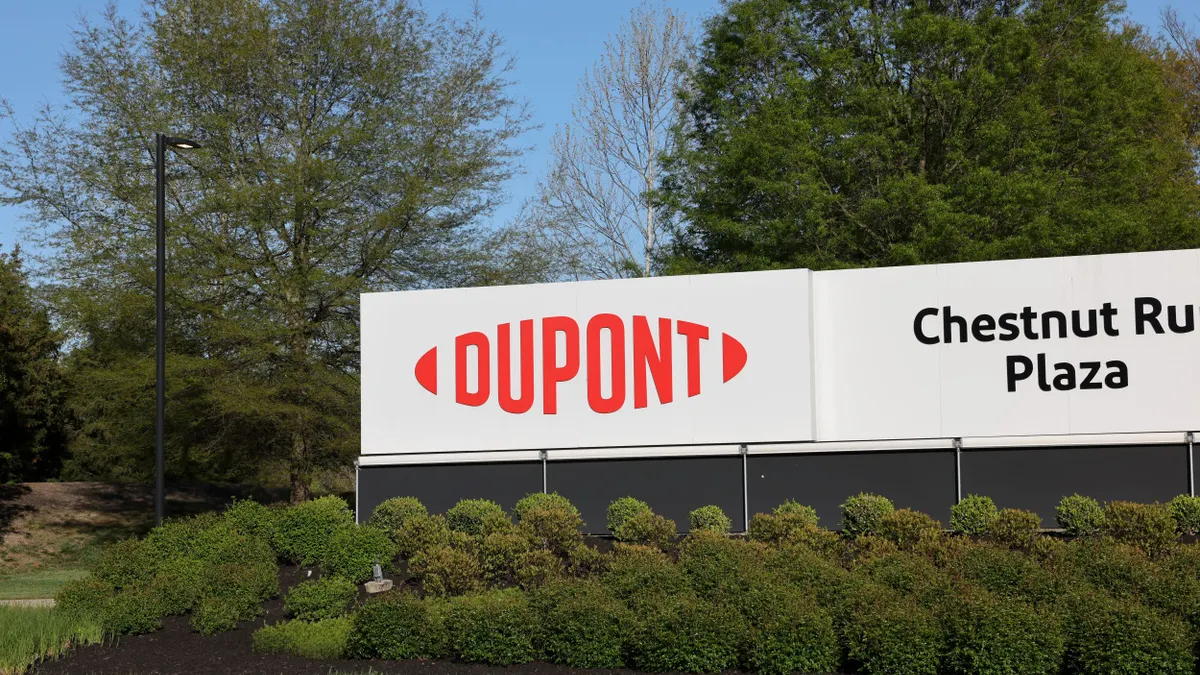 A red and white DuPont sign next to a black and white Chesnutt Run Plaza sign next to it.